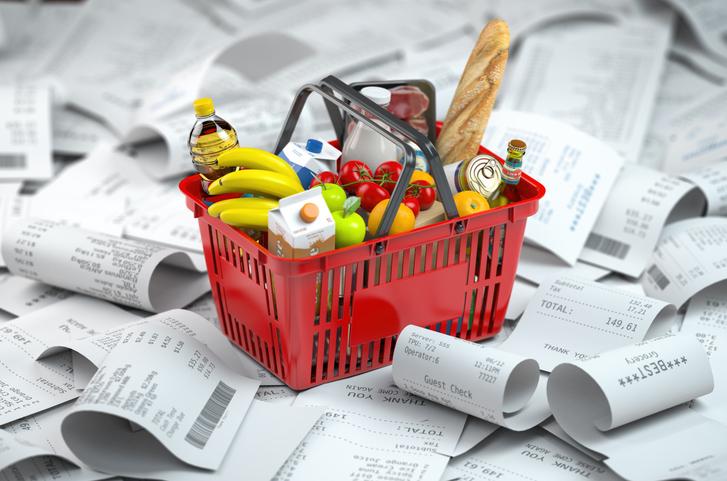 A shopping basket surrounded by a pile of billing receipts.